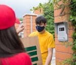 pexels-photo-8931654-8931654-1 Masked man receiving a delivery from a courier outdoors. Safety measures in place.